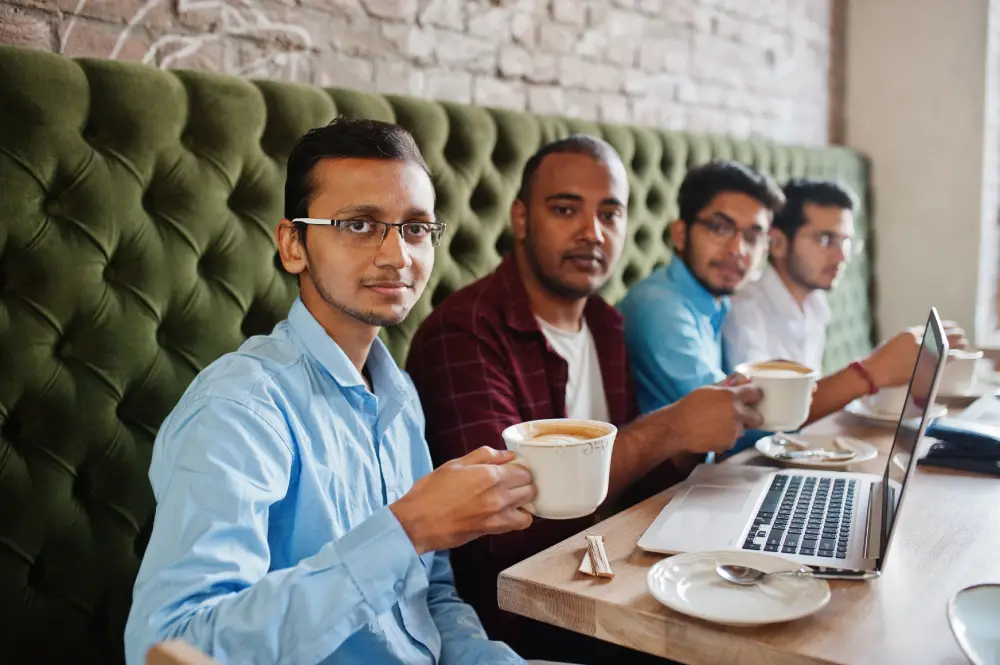 group of four south Asian men’s posed business meeting