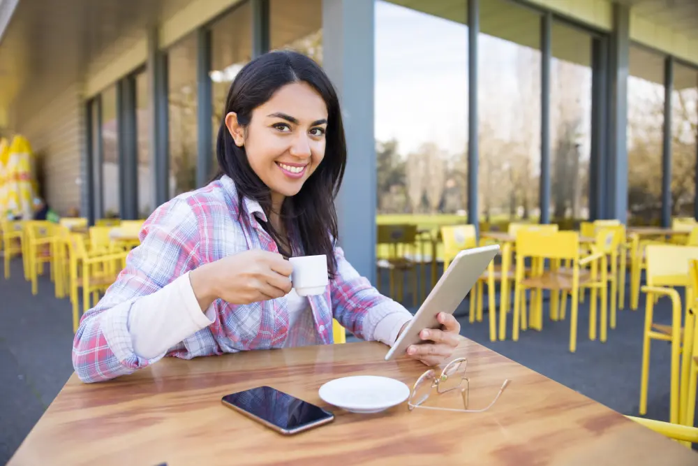 smiling woman using gadgets drinking coffee cafe